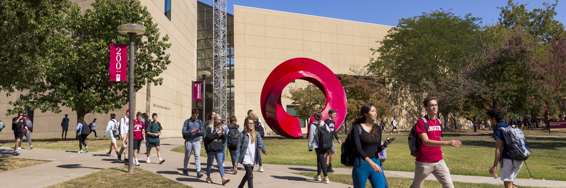 People walk on the sidewalks in front of the museum's main entrance.